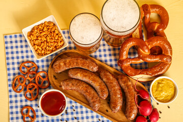 Glasses of cold beer and different snacks on yellow background. Oktoberfest celebration