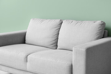 Cozy grey sofa near green wall