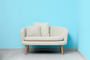 Cozy white sofa with pillows near blue wall