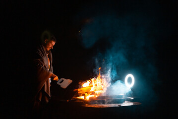Man preparing bbq grill to cook on fire. Outside dark shot. Freeze moment of fire