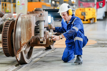 Engineers inspecting locomotive in railway engineering facility