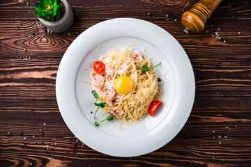 Pasta carbonara, spaghetti with ham, raw egg, cheese, tomatoes and microgreens, Italian food.