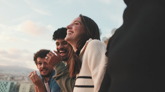 Close-up of young people, guys and girls friends standing hugging each other on the balcony looking at the beautiful views