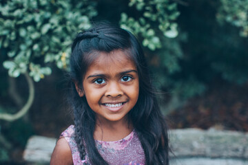 close up beautiful indian little girl in the park with trees and greenery
