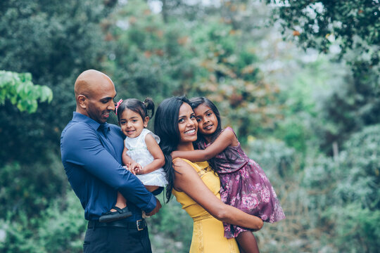 beautiful indian family standing and smiling in the park with trees and greenery