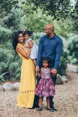 beautiful indian family standing and smiling in the park with trees and greenery