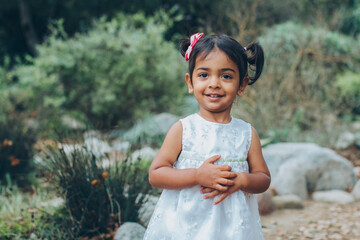 portrait of a beautiful indian little girl in the park with trees and greenery