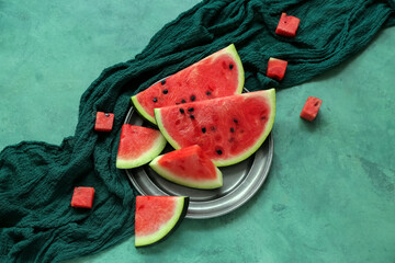 Plate with pieces of fresh watermelon on green background