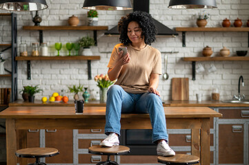 Young woman in jeans and beige tshirt in the kitchen