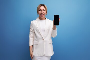 young blond manager woman in a white elegant jacket and skirt holds the phone vertically
