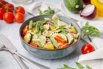 Bowl of tasty pasta salad with pepper and tomatoes on white background