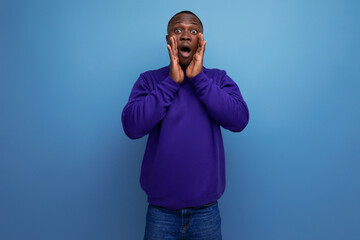 authentic handsome young african man in blue sweater on blue background with copy space