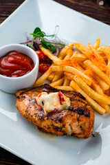 Fried chicken fillet with French fries, onion, cherry tomatoes and ketchup, closeup.