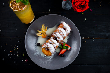 Donuts with sweet sauce, strawberries, blueberries, physalis, powdered sugar and lemonade, sweet breakfast.