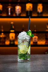 Mojito cocktail with lime slices, mint and ice cubes on the bar counter.