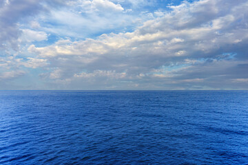 Blue ocean view with horizon and cloudy sky