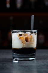 Cocktail White Russian with coffee liqueur, vodka, cream and ice in a glass.