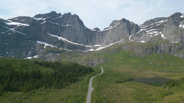 une longue route droite en direction d'une montagne en arc de cercle , en partie enneig&eacute;e