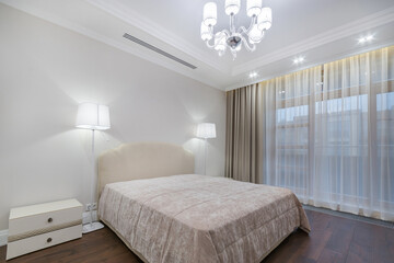 A luxurious bedroom decorated in pastel colors. Panoramic window with beautiful curtains.