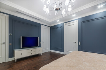 Stylish bedroom interior in neoclassical style. Dark parquet, white doors and gray-blue .walls.