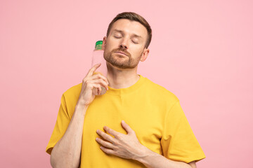 Overheated tired middle aged man suffers from heat, puts bottle of cold water to neck. Exhausted guy trying to cool down after sports training in hot summer day, feels dehydrated and thirsty. 