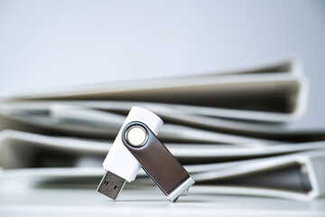 Usb flash drive stick in front of a heap of white file folders or ring binders, concept for space...