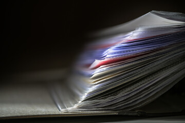 Close up of documents in transparent sleeves or punched pockets in a ring binder against a dark...