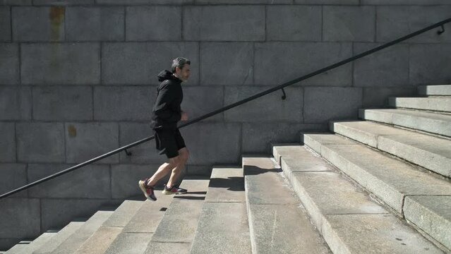 Male athlete running by stairs outdoors during workout. Sport Motivation. 40s Male Athlete Running Up On Urban Stairs Outdoors, Enjoying Morning Workout Slow Motion