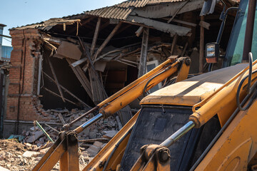 bulldozer bucket on the background of a destroyed house
