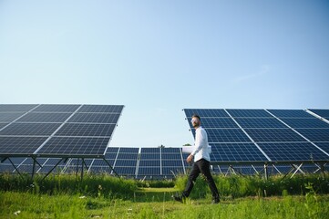 Male worker solar power plant on a background of photovoltaic panels.