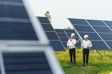The solar farm(solar panel) with two engineers walk to check the operation of the system,...