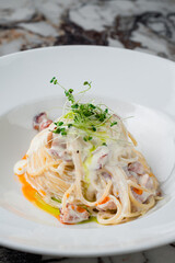 Italian lunch pasta with bacon, cream sauce and microgreens.