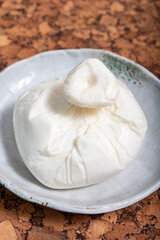 Fresh handmade soft Italian cheese from Puglia, white ball of burrata foglia saporosa or burratina cheese made from mozzarella and cream filling