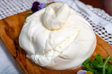 Eating of fresh handmade soft Italian cheese from Puglia, white balls of burrata foglia saporosa or burratina cheese made from mozzarella and cream filling close up