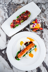 Salmon fillet with spinach, salad with tuna, avocado, algae, strawberries, sesame seeds and dessert.