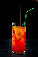 Alcoholic cocktail Tequila Sunrise with orange slices in a glass.