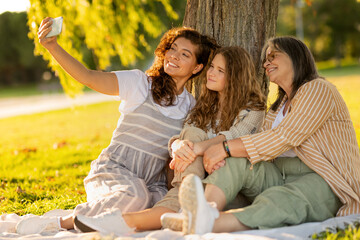 Cheerful caucasian multi-generation different women rest, enjoy picnic in park, take selfie on smartphone