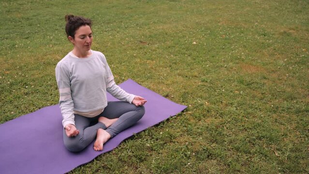Pregnant woman doing yoga exercise outdoors