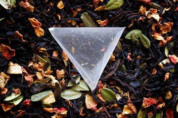 An inverted pyramid tea bag with black flavored tea, with the addition of fruits and berries, lies...