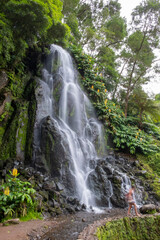 Waterfall in the Botanical Garden of Ribeira do Guilherme in Nordeste with tourists, Sao Miguel island in the Azores.