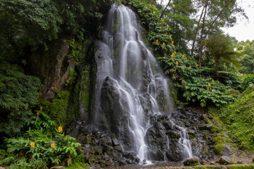 Fototapeta na wymiar Waterfall in the Botanical Garden of Ribeira do Guilherme in Nordeste with tourists, Sao Miguel island in the Azores.
