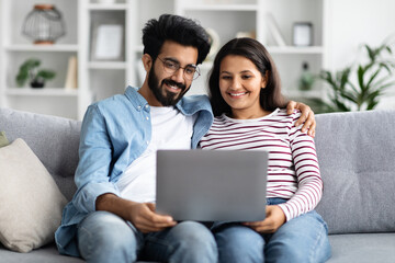Sweet hindu couple watching movie on laptop at home
