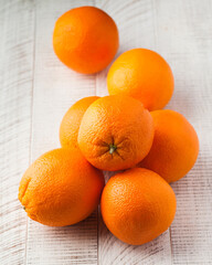 A group of ripe oranges on a white wooden background. Citrus fruits. 