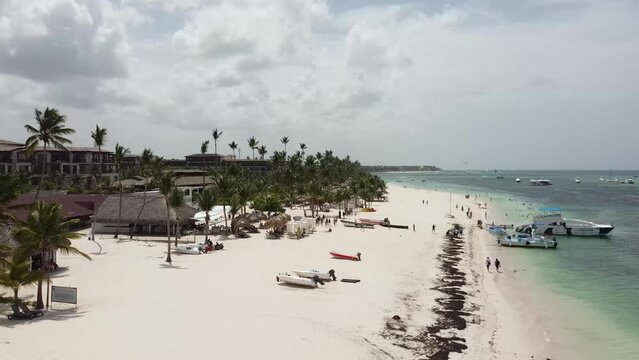 Vuelo de drone en playas de punta cana republica dominicana, con algunos barcos parados en la orilla, clima soleado y cielo limpio azul.