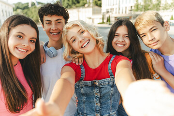 Group of smiling friends, multiracial teenagers taking selfie looking at camera on urban street....