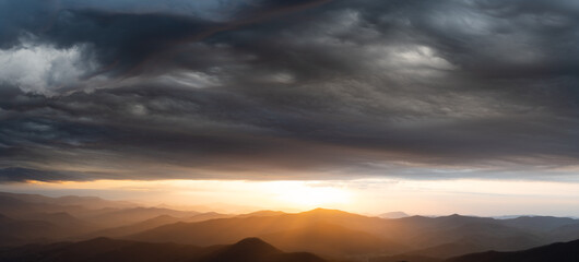 Sunrise fighting for the sky during a storm over mountains