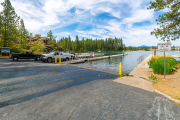 Fototapeta na wymiar Trucks with trailers lower boats into the Spokane River from the boat ramp launch at Q'Emiln Park in the rural town of Post Falls, a suburb of the Coeur d'Alene Idaho region of North Idaho.