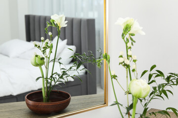 Stylish ikebana with beautiful flowers and green branch carrying cozy atmosphere at home