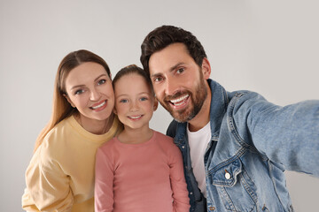 Obraz premium Happy family taking selfie on light grey background