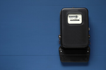 Electricity meter on blue wooden wall, space for text
